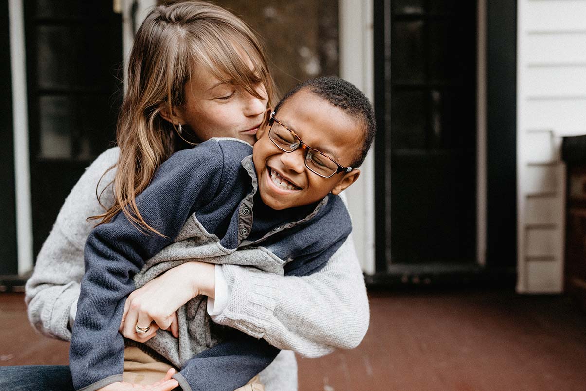 Mother and son cuddling and hugging on the front porch in the cold weather