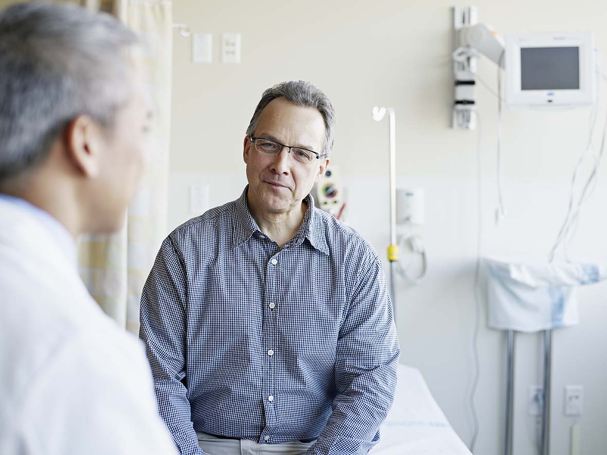 Doctor talks to mature male patient while in a doctor’s office.